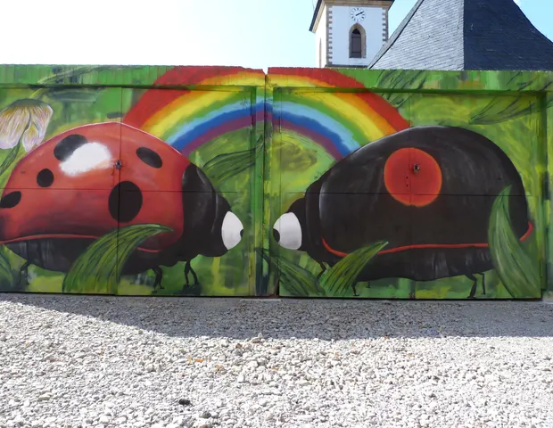 Bunte Naturwand mit Marienkäfern und Regenbogen
